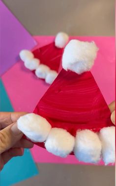 someone is making a santa hat out of construction paper and pom - poms