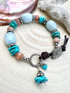 Such a great mix of gemstones in this fun bracelet! The stones in the bracelet are rondel faceted sunstone beads, rustic robins egg blue turquoise and large aquamarine nugget beads. There are gunmetal cz crystal spacers between the beads.  The bracelet closes with a square filigree pewter button and a leather toggle.  The bracelet has a tiny turquoise heart charm and a turquoise beaded dangle.  Bracelet measures approximately 7 1/2  inches long. All metal is silver plated Turquoise Aquamarine Beaded Bracelets With Natural Stones, Bohemian Amazonite Hand-strung Beaded Bracelets, Handmade Turquoise Aquamarine Bracelets, Turquoise Gemstone Beaded Bracelets In Bohemian Style, Bohemian Turquoise Gemstone Beaded Bracelets, Bohemian Amazonite Bracelets With Gemstone, Bohemian Amazonite Gemstone Bracelets, Rustic Turquoise Beaded Bracelets With Natural Stones, Bohemian Aquamarine Jewelry In Turquoise