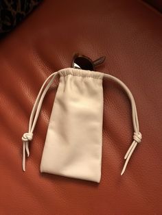 a small white pouch sitting on top of a red leather couch next to a pair of sunglasses