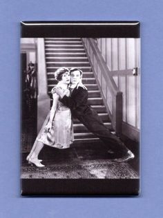 an old black and white photo of two people hugging in front of some stairs with their arms around each other