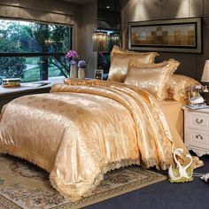 a bed with gold comforters and pillows in a room next to a window,