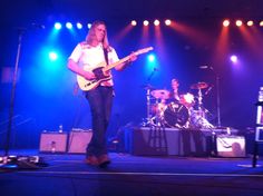 a man standing on top of a stage holding a guitar