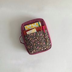 a pink case filled with lots of different items on top of a white table next to a cup