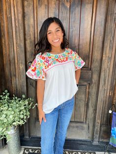 Fiesta Style Top with Signature Multi-Colored Embroidery and Butterfly Sleeves Bring the vibrant spirit of a fiesta to your wardrobe with our Fiesta Style Top. Featuring our signature multi-colored embroidery and elegant butterfly sleeves, this top is perfect for adding a splash of color and a touch of sophistication to any outfit. Designed for both comfort and style, it's a must-have for any fashion-forward wardrobe. Key Features: Fiesta-Inspired Design: Celebrate in style with a top that embodies the festive spirit with its lively colors and design. Signature Multi-Colored Embroidery: Our exclusive multi-colored embroidery adds a unique and eye-catching detail to this top. Butterfly Sleeves: The flowing butterfly sleeves offer a graceful and feminine touch, enhancing the overall look. Co Festive White Top With Embroidered Sleeves, Multicolor Cotton Flutter Sleeve Top, Multicolor Floral Embroidered Top For Spring, Multicolor Floral Print Embroidered Top For Spring, Spring Multicolor Floral Embroidered Top, Multicolor Cotton Tops With Flutter Sleeve, Spring Crew Neck Top With Embroidered Neckline, Summer Embroidered Blouse With Flutter Sleeves, Spring Embroidered Neckline Crew Neck Top