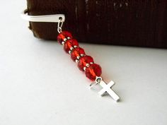 a bookmark with a cross and beads hanging from it's side on a table