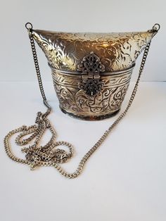 "This OOAK gorgeous vintage silver toned metal purse is the perfect next addition to your purse collection! This stunning unique bag is made of silver tone brass and has fabulous embossing motif, a long chain strap and ornate hinged clasp. The lining on the inside is a black velvet. This vintage metal purse is perfect for both casual and formal outfits alike. Get this amazing purse for yourself or for someone in your life who loves vintage accessories! Excellent vintage condition Height 5\" Width 6\" on top, 3.75\" on bottom Length 3\" Opening 4\" x 3\" 44\" chain US SHIPPING FREE  International shipping, please see the rate  Please add our shop as a ❤ favorite so you can find us again!  Please check out linktr.ee/minxandonyx  Thank you for shopping at Minx and Onyx, your favorite eclectic Silver Luxury Clutch Shoulder Bag, Luxury Silver Clutch Shoulder Bag, Silver Bucket Evening Bag, Metallic Metal Evening Bag, Metallic Metal Evening Bags, Silver Formal Bucket Evening Bag, Silver Bucket Shoulder Bag For Party, Elegant Metal Rectangular Shoulder Bag, Silver Metal Rectangular Bag