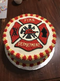 a fire department cake with red and yellow frosting on a table next to a cup