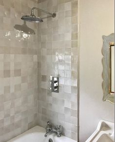 a white bath tub sitting next to a mirror in a bathroom under a faucet