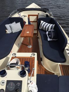 the inside of a boat with blue cushions on it's deck and wooden flooring