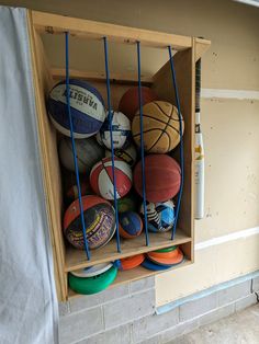 basketballs and other sports balls are stored in a cabinet