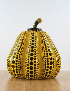 a yellow and black vase sitting on top of a wooden table