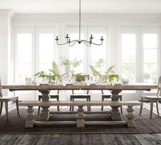 a dining room table and chairs in front of two large windows with white trimmings