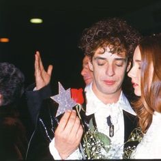 two people standing next to each other and one is holding a star ornament