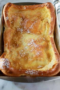 a pan filled with bread covered in powdered sugar on top of a marble counter