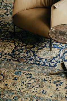 a brown chair sitting on top of a blue and beige rug next to a table