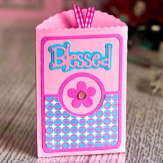 a small pink box with a flower on the front and wording, bassed