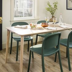 a dining table with green chairs and plates on it