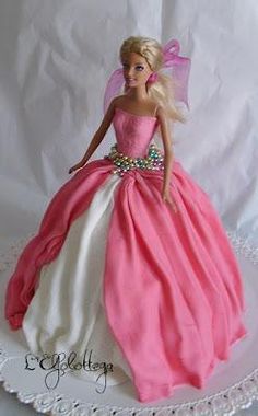 a barbie doll in a pink and white dress on a cake plate with lace trim