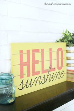 a wooden sign that says hello sunshine on it next to some books and a jar