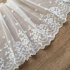 the white lace is on top of a piece of fabric that has flowers and leaves