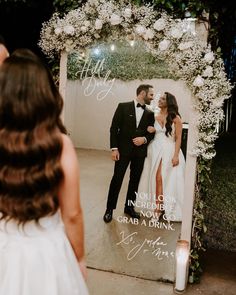 a bride and groom standing in front of a mirror with their wedding pictures on it