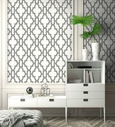 a white dresser sitting next to a wall with a plant on top of it near a bed