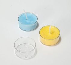 two candles sitting next to each other on top of a white table with one candle in the middle