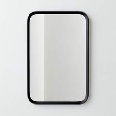 a square mirror mounted to the side of a white wall next to a black frame