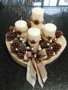 a wooden plate topped with candles and pine cones