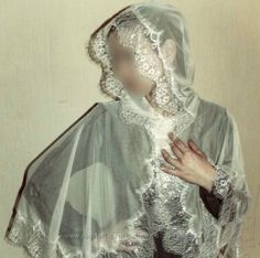 a woman wearing a veil and holding her hands to her chest, with the back of her head covered in lace