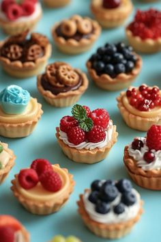 there are many small pastries on the table with berries and blueberries in them