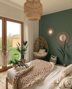 a bedroom with green walls and wicker hanging chairs in the corner next to a bed