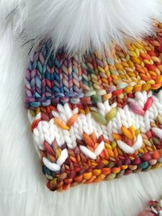 a multicolored knitted hat laying on top of white fur