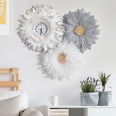 two clocks are hanging on the wall next to plants and other decorations in vases