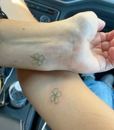 two people with tattoos on their arms are sitting in a car and one is holding the other's hand