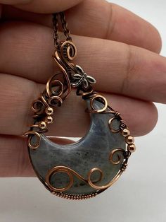 a person holding up a necklace with an oval shaped pendant on it's side