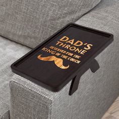 a tray that says dad's throne resting on the couch with a moustache