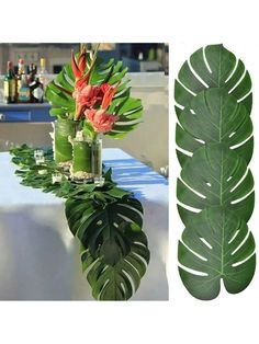 a table topped with a vase filled with flowers next to a large leafy plant