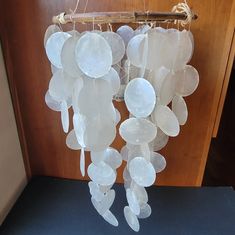 a wind chime made out of plastic plates hanging from a wooden door with rope