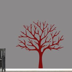 a red tree with no leaves on it in the corner of a room next to a black chair