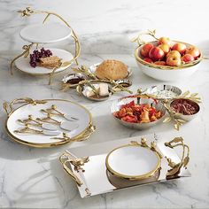 a table topped with plates and bowls filled with fruit on top of a marble counter