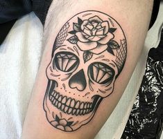 a black and white skull with a rose tattoo on it's arm, sitting on a bed