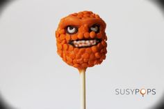 an orange lollipop with googly eyes and teeth on it's stick