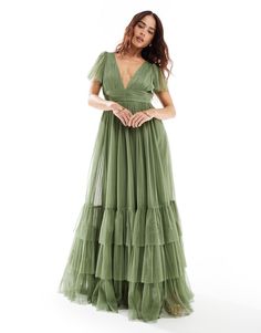 a woman in a green dress posing for the camera with her hands on her hips