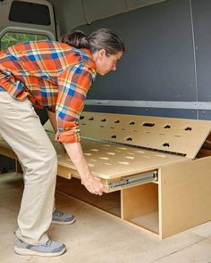 a woman bending over to look at the bottom of a drawer that has holes in it