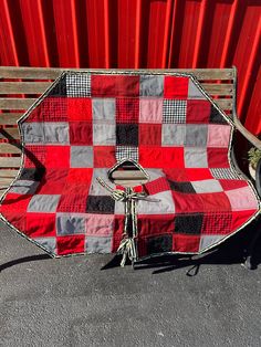 a red and black checkered blanket sitting on top of a wooden bench next to a red wall