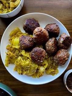 meatballs and noodles on a white plate next to two bowls of chili sauces