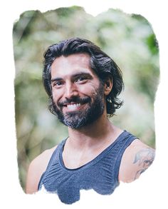 a man with long hair and beard wearing a blue tank top smiling at the camera