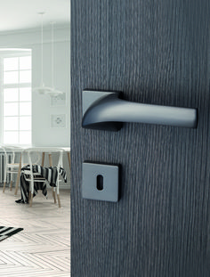 an open door with a black handle on it and a white dining room table in the background