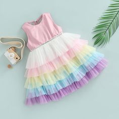 This charming, rainbow layered dress will make your little princess look just as glamorous as you! It features a multicolor, layered skirt, a tulle bodice and a bow at the back. Made for special occasions, this versatile dress can also be worn casually. Influencer @helena.modenezi Material: Cotton, polyester Rainbow Frocks For Kids, Playful Multicolor Tiered Dress, Pink Layered Hem Tiered Dress, Pink Tiered Skirt Dress With Layered Hem, Summer Tiered Tutu Dress With Ruffles, Multicolor Sleeveless Princess Dress For Dress-up, Summer Rainbow Dress For Dress-up, Rainbow Dress For Summer Dress-up, Rainbow Dresses For Summer Dress-up